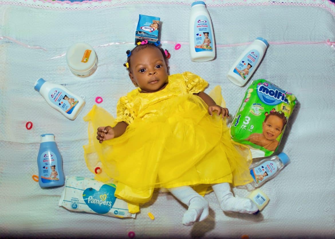 baby in yellow dress lying on bed