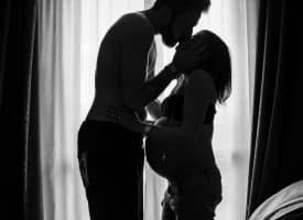 man standing near window kissing woman