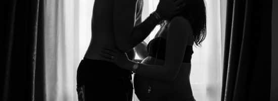 man standing near window kissing woman